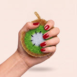 A hand squeezing the kiwi scrubber to show how soft it is