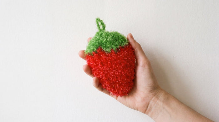 The strawberry frubbies scrubber held in an open hand